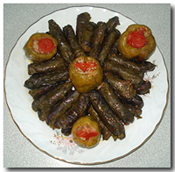 Dolmades (Stuffed Grape Leaves) arranged with stuffed bell peppers.